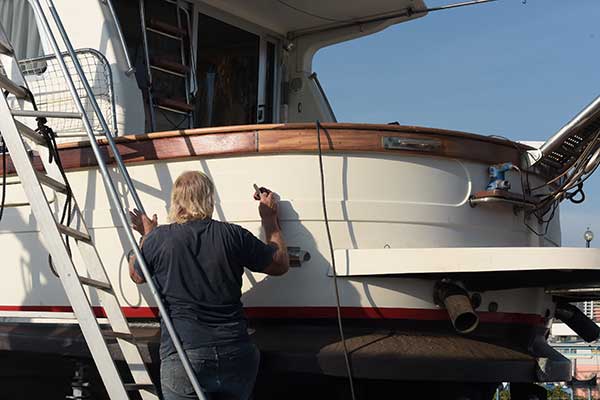 Ein Mann pflegt sein Boot mit Koleen Top-Cover um den Gelcoat zu schützen.