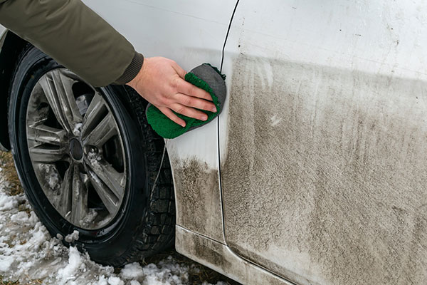 Ein dreckiges Auto wird mithilfe eines Schwamms gereinigt