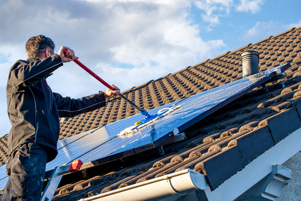 Mann reinigt Solarpanel auf Dach - mit Photovoltaik clean & protect von Koleen